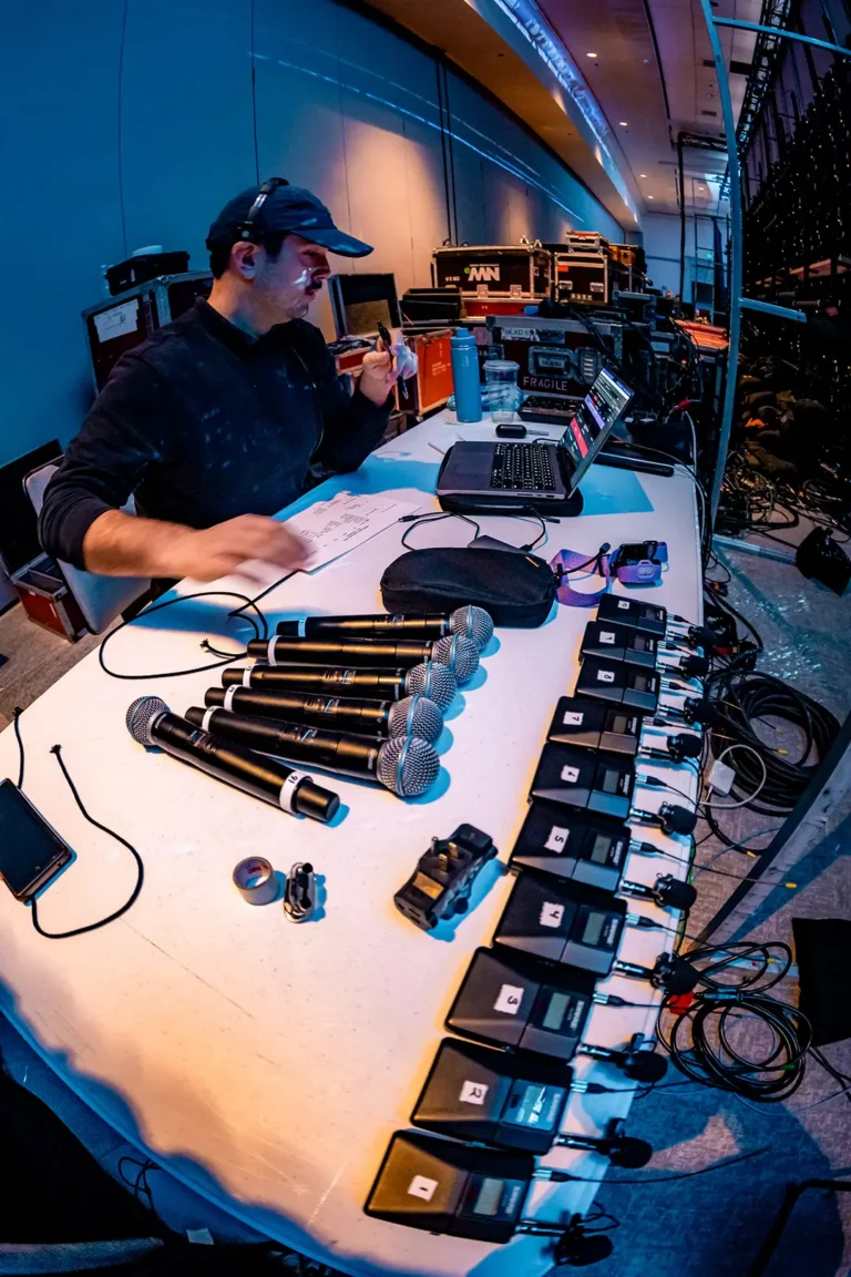 Audio technician organizing wireless microphones and production equipment during audio visual event production setup