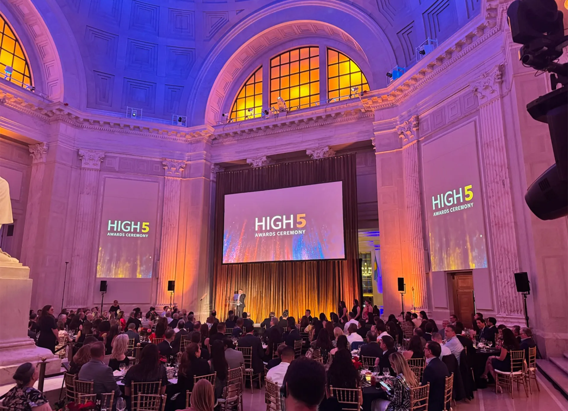 Corporate event staging with projection screens and colorful lighting for the HIGH5 Awards Ceremony.