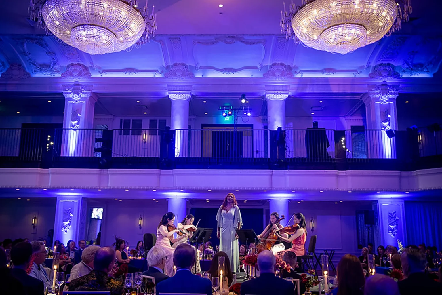 Showorks AV lights a ballroom in blue and purple as a vocalist performs with a string ensemble.
