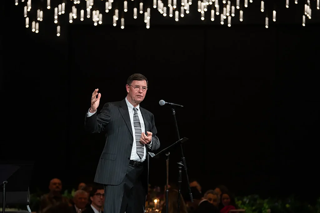 Showorks AV supports a gala speaker onstage beneath hanging lights.